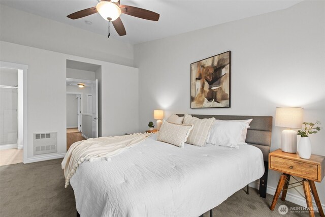 carpeted bedroom with heating unit, baseboards, ceiling fan, and ensuite bath