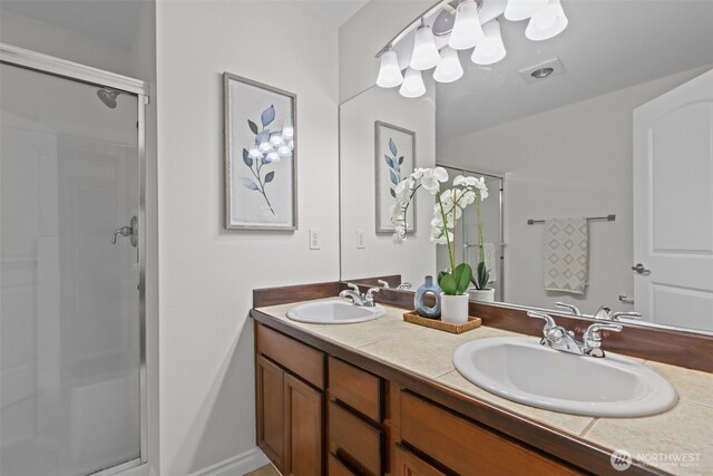 full bath with double vanity, a shower stall, and a sink