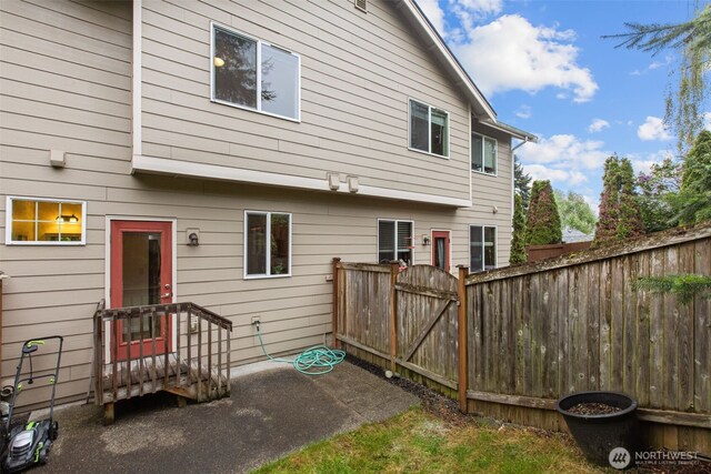 rear view of house featuring fence and a gate