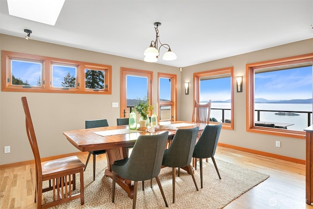 dining room with baseboards, an inviting chandelier, a healthy amount of sunlight, and light wood-style flooring