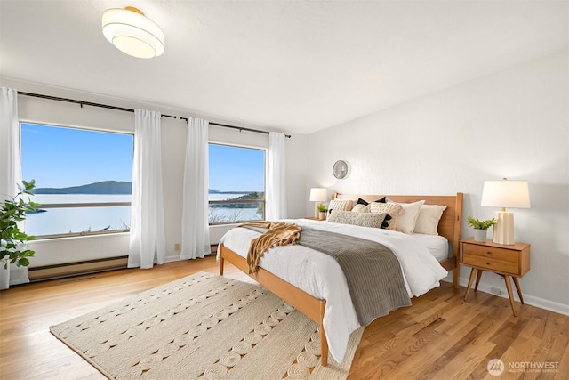 bedroom featuring a baseboard heating unit and light wood-style floors