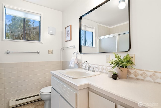 full bath with vanity, baseboard heating, toilet, and a healthy amount of sunlight