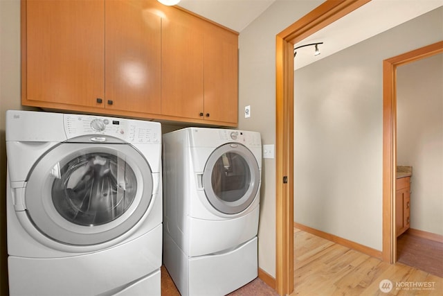 washroom with cabinet space, baseboards, washer and clothes dryer, and light wood-style flooring