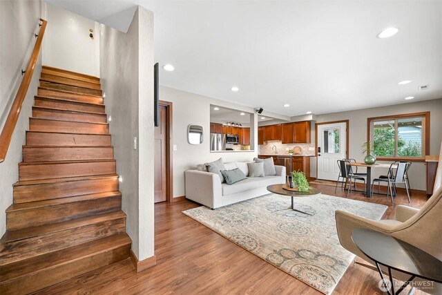 living room featuring recessed lighting, baseboards, wood finished floors, and stairway
