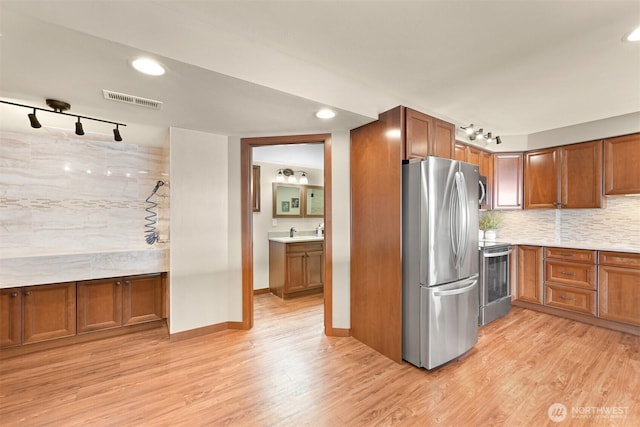 kitchen featuring track lighting, light wood finished floors, appliances with stainless steel finishes, and visible vents