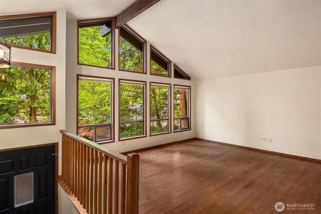 interior space with baseboards, wood finished floors, and high vaulted ceiling