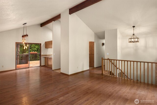 spare room with an inviting chandelier, hardwood / wood-style flooring, and beam ceiling