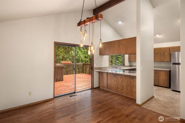kitchen featuring brown cabinets, a sink, light countertops, beamed ceiling, and freestanding refrigerator