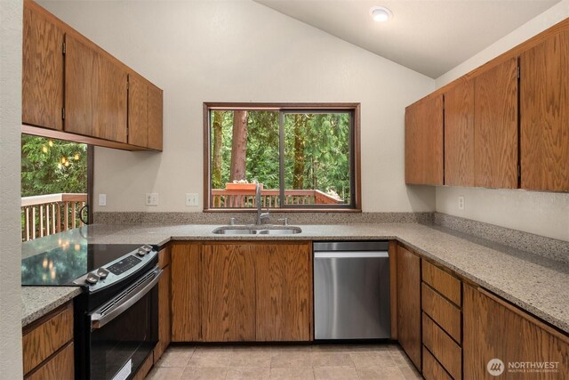 kitchen featuring brown cabinets, a sink, light countertops, lofted ceiling, and stainless steel appliances