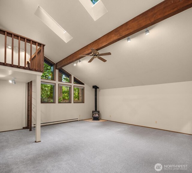 additional living space featuring vaulted ceiling with skylight, carpet floors, baseboard heating, and a wood stove
