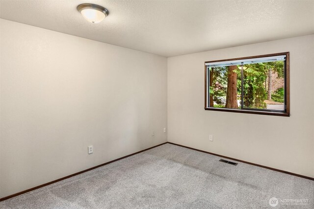 unfurnished room featuring carpet flooring, a textured ceiling, baseboards, and visible vents