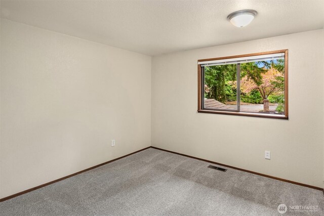 empty room featuring carpet floors, baseboards, and visible vents
