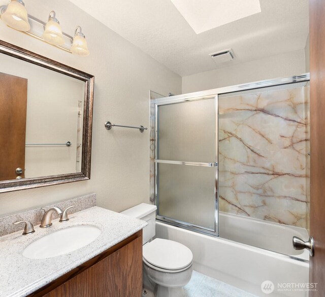 bathroom featuring visible vents, a skylight, vanity, bath / shower combo with glass door, and toilet