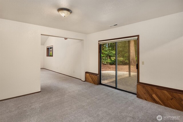 empty room featuring carpet floors, a textured ceiling, and visible vents