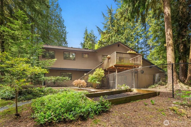 rear view of house with a garden, a wooden deck, stairway, and fence