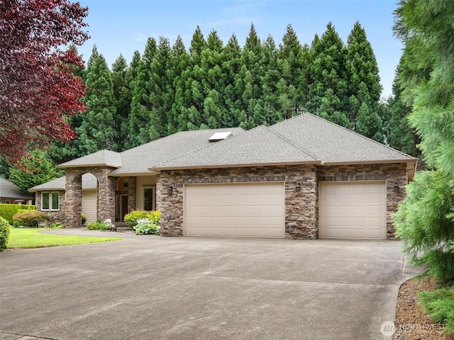 view of front of property with concrete driveway, roof with shingles, an attached garage, and stone siding