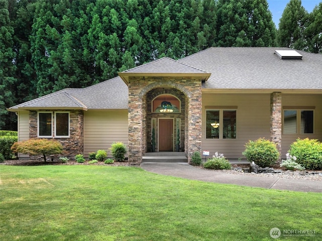 view of front facade with stone siding, a front yard, and roof with shingles