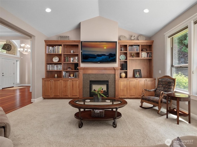 living area featuring carpet, vaulted ceiling, a fireplace, and a healthy amount of sunlight