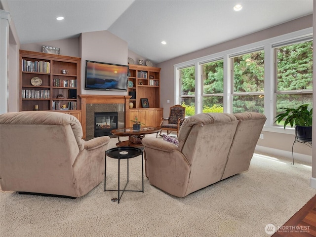 living room with recessed lighting, a glass covered fireplace, and lofted ceiling
