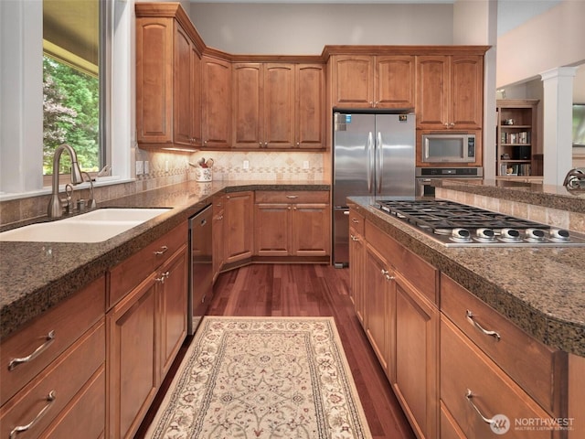 kitchen featuring dark wood-style flooring, appliances with stainless steel finishes, brown cabinetry, and a sink