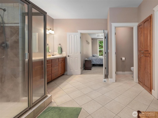 ensuite bathroom featuring connected bathroom, vanity, toilet, tile patterned floors, and a shower stall