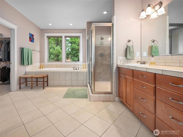 full bathroom featuring vanity, a stall shower, a bath, and tile patterned floors