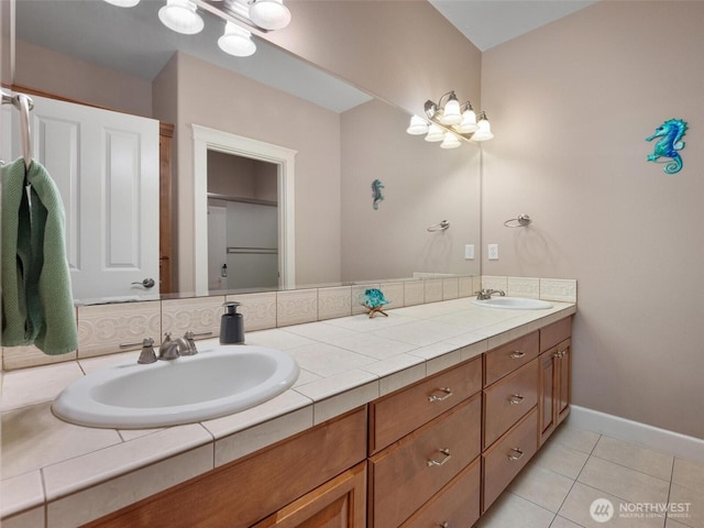 full bath featuring double vanity, a sink, baseboards, and tile patterned floors