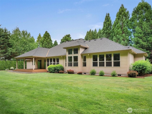 rear view of house featuring a shingled roof, a yard, and crawl space