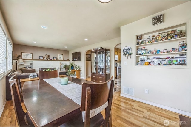 dining area with visible vents, wood finished floors, baseboards, recessed lighting, and arched walkways