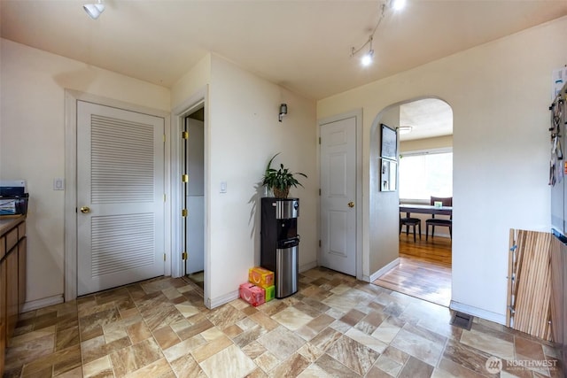 entryway with arched walkways, baseboards, and stone finish flooring