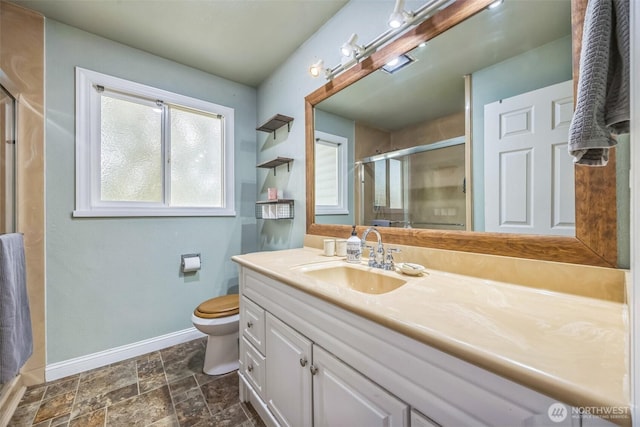 full bath with vanity, toilet, baseboards, stone finish flooring, and a stall shower