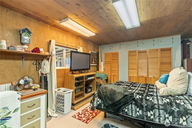 bedroom with wooden ceiling, light carpet, two closets, and wood walls