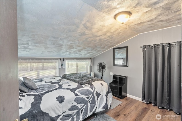 bedroom featuring baseboards, wood finished floors, and vaulted ceiling
