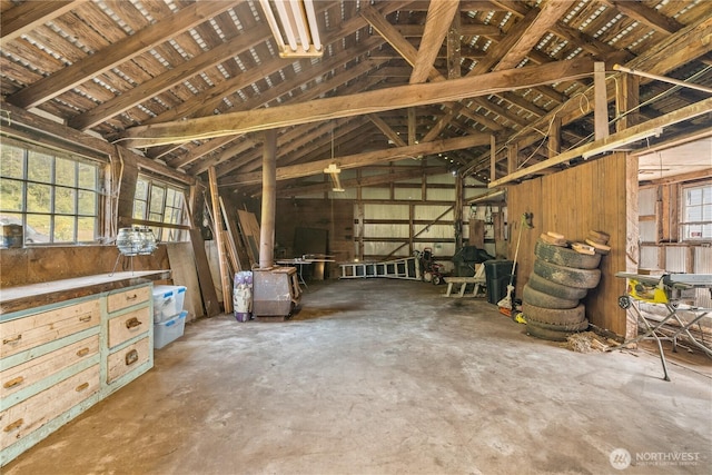 misc room featuring unfinished concrete floors, wooden walls, and lofted ceiling