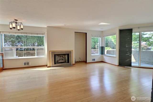 unfurnished living room featuring visible vents, a fireplace with flush hearth, and wood finished floors
