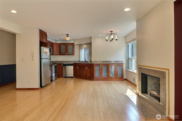 kitchen with appliances with stainless steel finishes, baseboards, light wood finished floors, glass insert cabinets, and recessed lighting