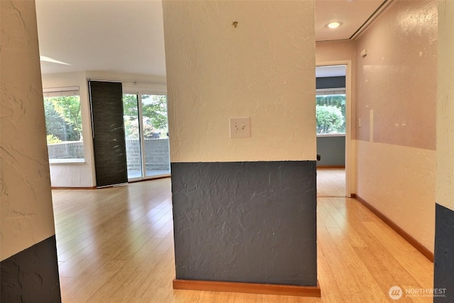 kitchen featuring baseboards, a textured wall, and wood finished floors
