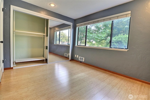 unfurnished bedroom featuring visible vents, baseboards, and wood finished floors