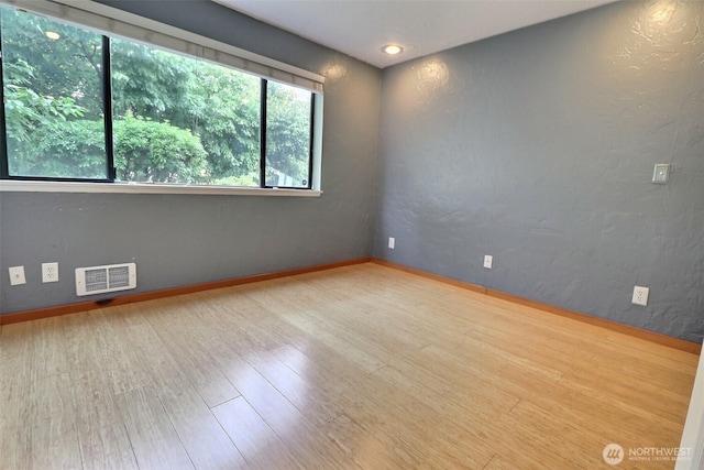 empty room with baseboards, visible vents, and wood finished floors