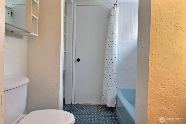 full bathroom with tile patterned flooring, shower / tub combo with curtain, a textured wall, and toilet