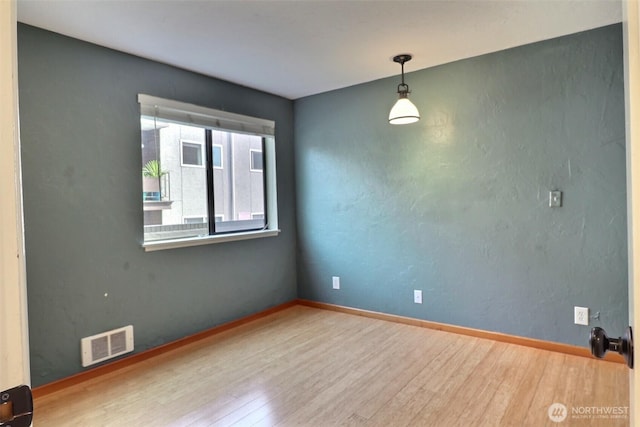 empty room with visible vents, baseboards, and wood finished floors