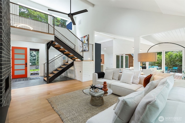 living area featuring a ceiling fan, stairs, wood finished floors, and a healthy amount of sunlight