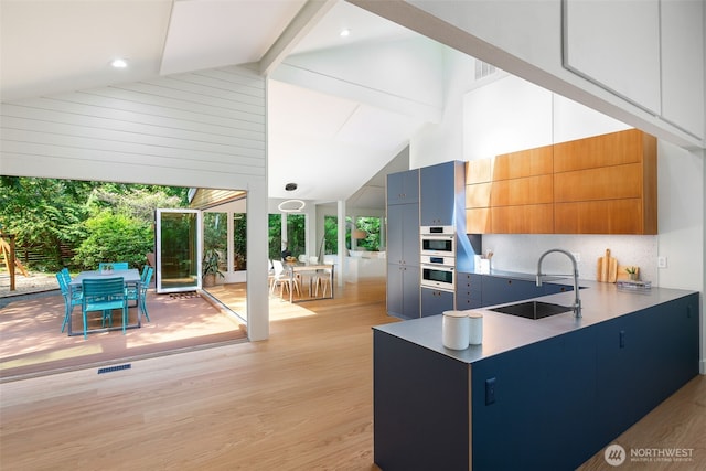 kitchen with a sink, beam ceiling, light wood-style floors, high vaulted ceiling, and decorative backsplash