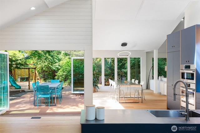 entryway with a sink, visible vents, wood finished floors, and lofted ceiling