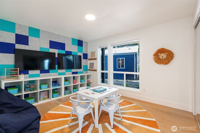 recreation room featuring baseboards and wood finished floors