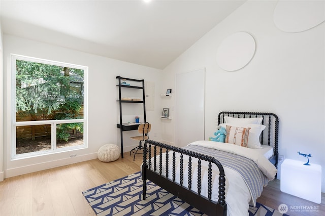 bedroom with wood finished floors and lofted ceiling