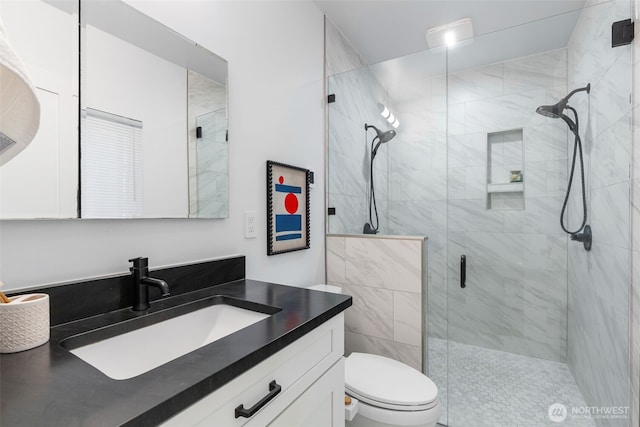 full bathroom featuring vanity, a shower stall, and toilet