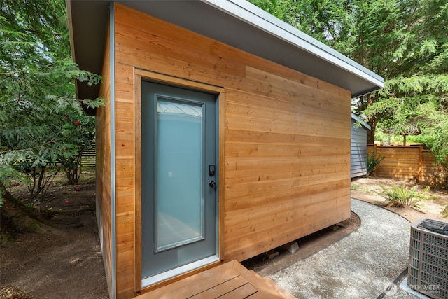 view of outdoor structure featuring central AC unit and fence