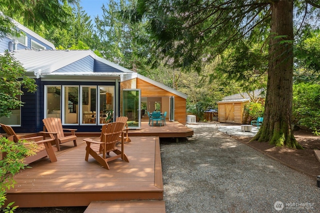 back of property featuring a deck, an outbuilding, and a storage unit