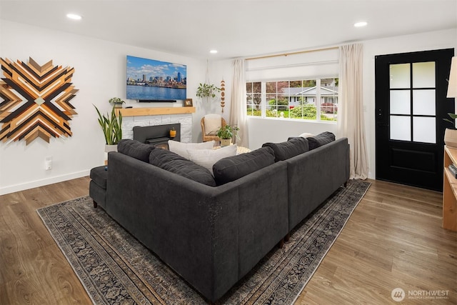 living area featuring baseboards, a stone fireplace, recessed lighting, and wood finished floors